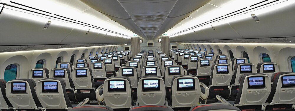 Inside an airplane, passengers seated on seats, ready for takeoff.